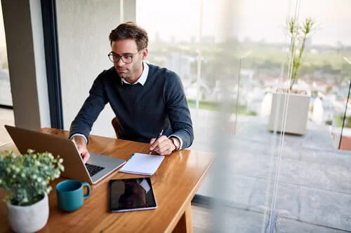 Salarié sur assis à une table face à son ordinateur recherchant quels sont les dispositifs pour se former Salarié sur assis à une table face à son ordinateur recherchant quels sont les dispositifs pour se former