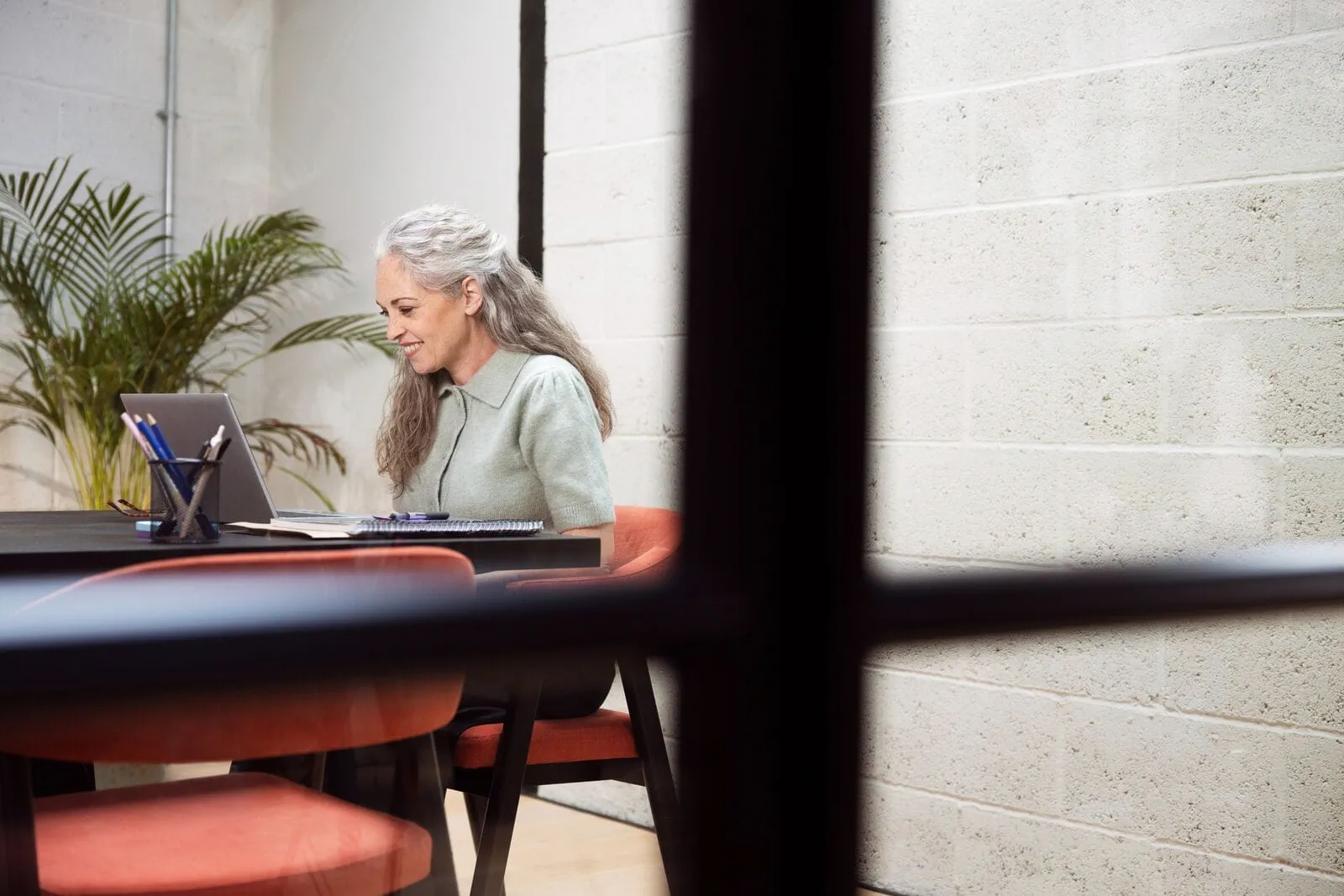 Professionnelle souriante travaillant sur ordinateur, représentant les métiers verts et la transition écologique en entreprise. Professionnelle souriante travaillant sur ordinateur, représentant les métiers verts et la transition écologique en entreprise.