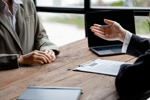 personne vêtue d’une chemise et d’un long manteau, détaillant son parcours professionnel face au recruteur lors d’un entretien professionnel  
