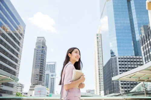 A businesswoman holding a report, with office buildings in the background A businesswoman holding a report, with office buildings in the background