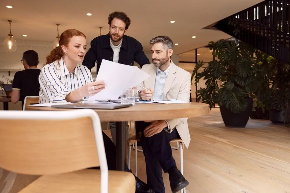 Trois recruteurs à leur bureau échangeant sur l’expérience candidat afin d’optimiser leurs recrutements. 