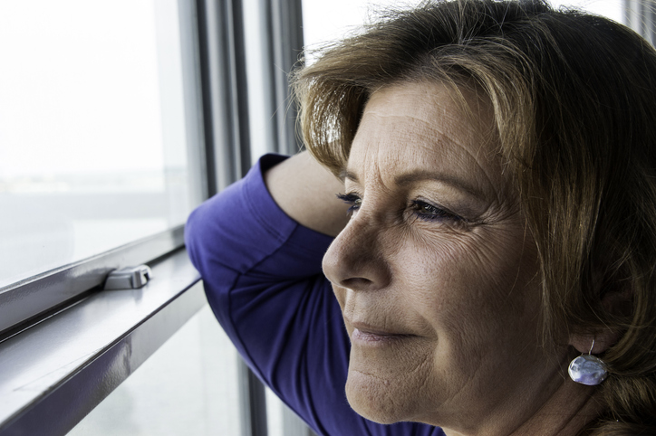 mature woman smiling while looking out a window