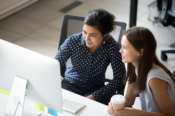 young women sitting together at desk in office