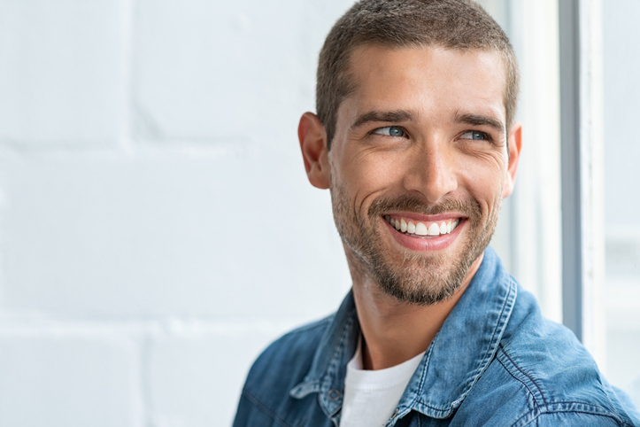 Confident young man looking away with big smile