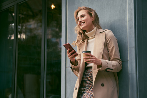woman holding a phone and a coffee cup