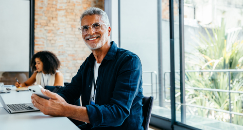 A senior businessman smiling during a team meeting A senior businessman smiling during a team meeting