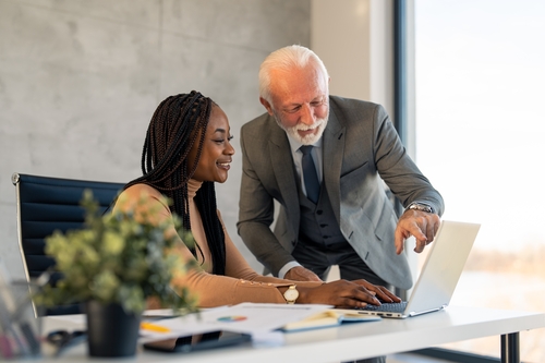 A senior businessman and a younger colleague looking at a laptop A senior businessman and a younger colleague looking at a laptop