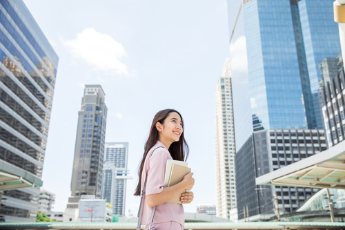 A businesswoman holding a report, with office buildings in the background A businesswoman holding a report, with office buildings in the background