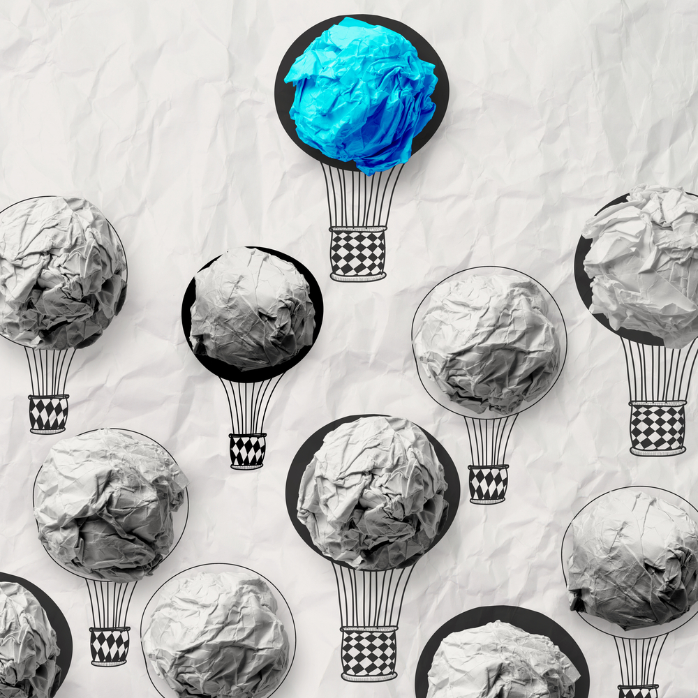 blue balloon rising above gray balloons