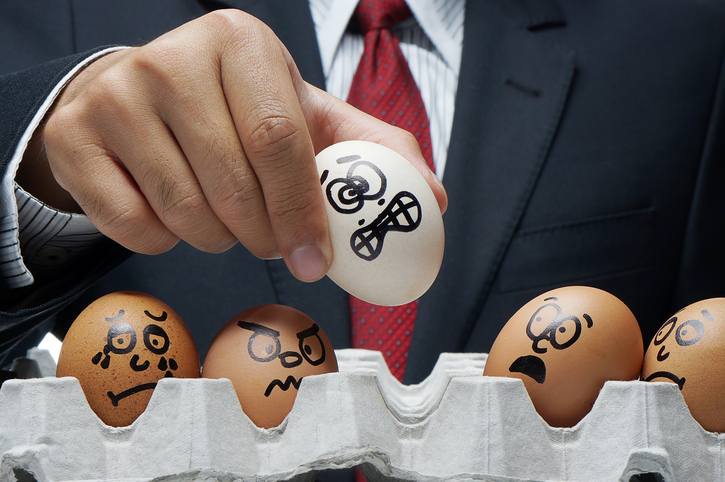man pulling bad egg out of carton of eggs