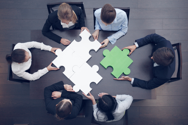 business people putting together a large puzzle