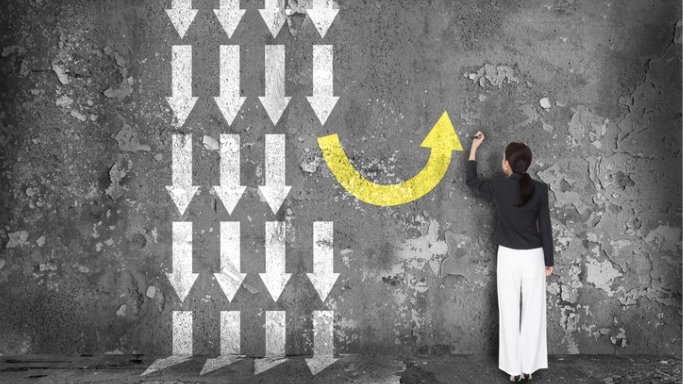 woman drawing an arrow going in the opposite direction of all other arrows