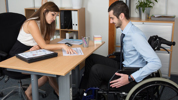 man using wheelchair talking to an officemate